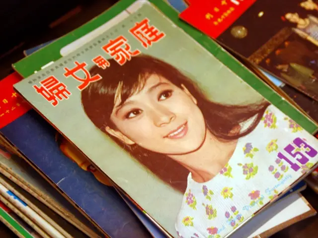 There are collection of magazines kept on a table,on the first magazine there is an image of a...