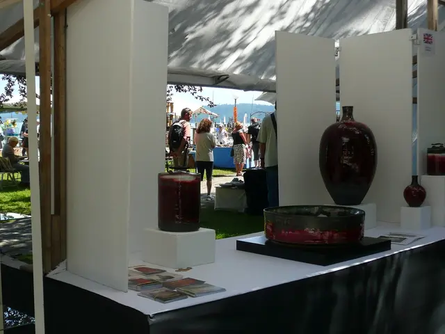 In this image there is a table under the tent. On the table there are books and sculptures. In the...