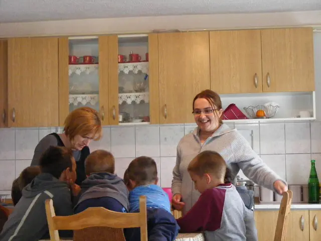In this picture there are five kids sitting on the chair and the lady to the right side is standing...