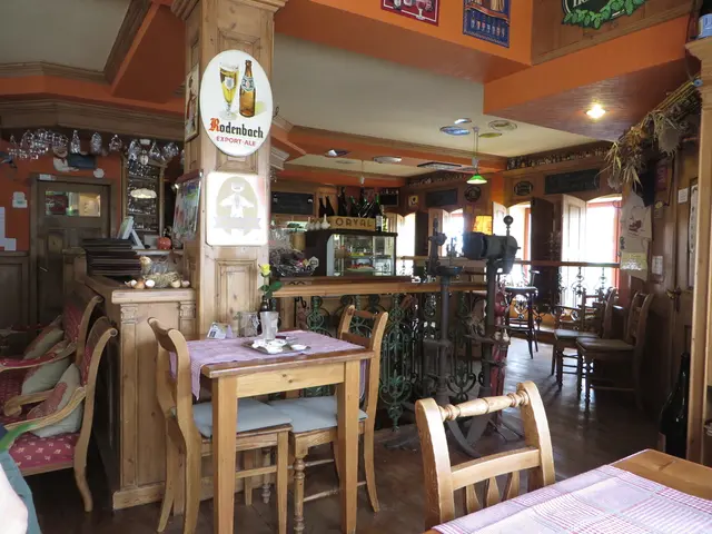 In the center of the image there is a wall, roof, pillar, chairs, tables, tablecloths, lights,...